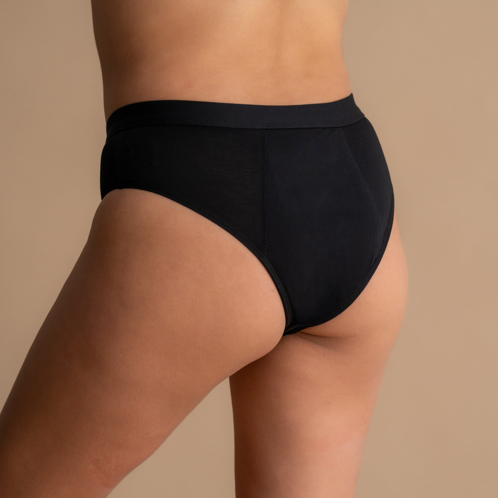 Zadnji pogled na model v črni Floena Leakproof Everyday Bamboo Bikini, bambusove menstrualne hlačke, z gladkim pasom in brezšivnim dizajnom