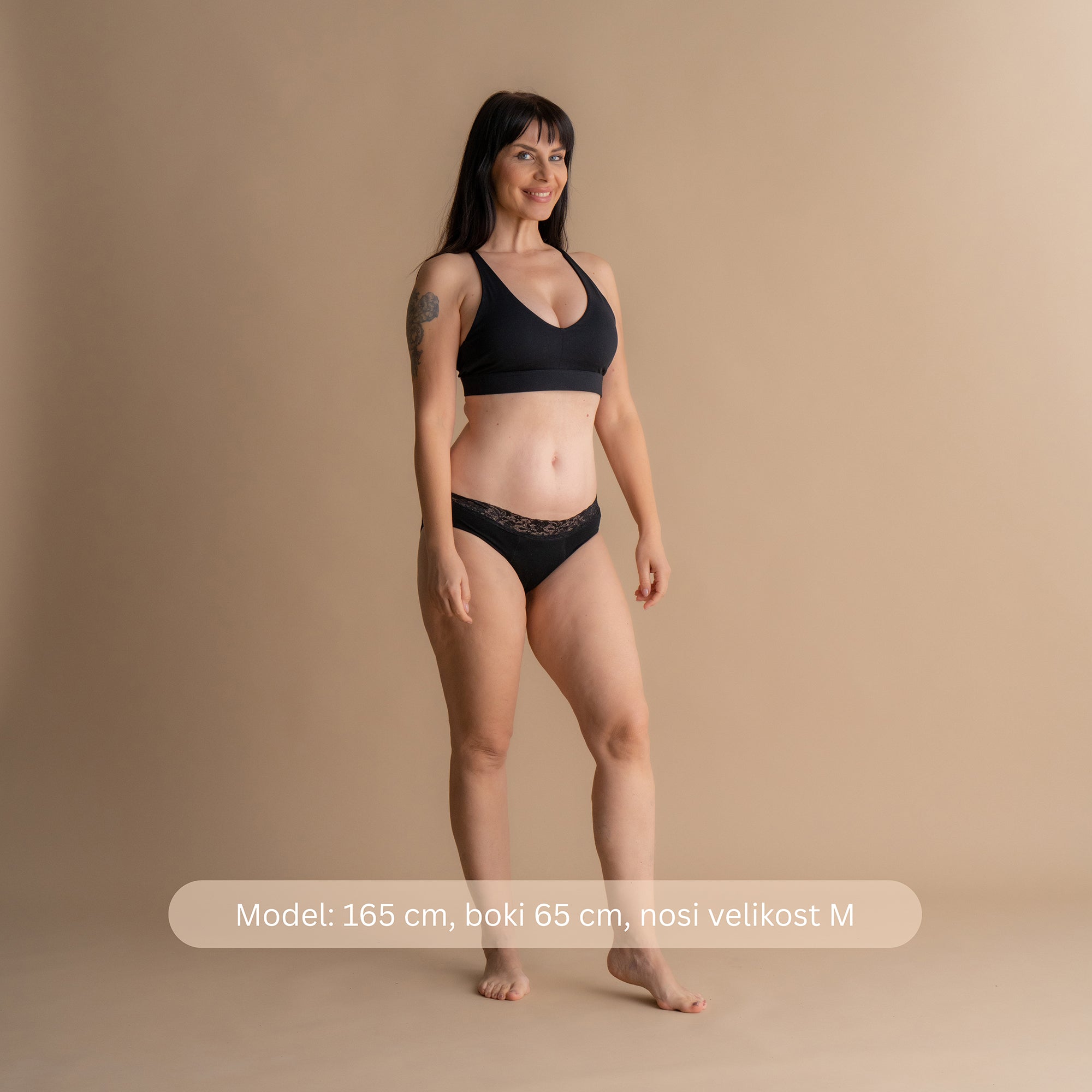 Model višine 165 cm z boki 65 cm nosi velikost M Floena Leakproof Comfort Brief, črne čipkaste menstrualne hlačke, z navedbo mere