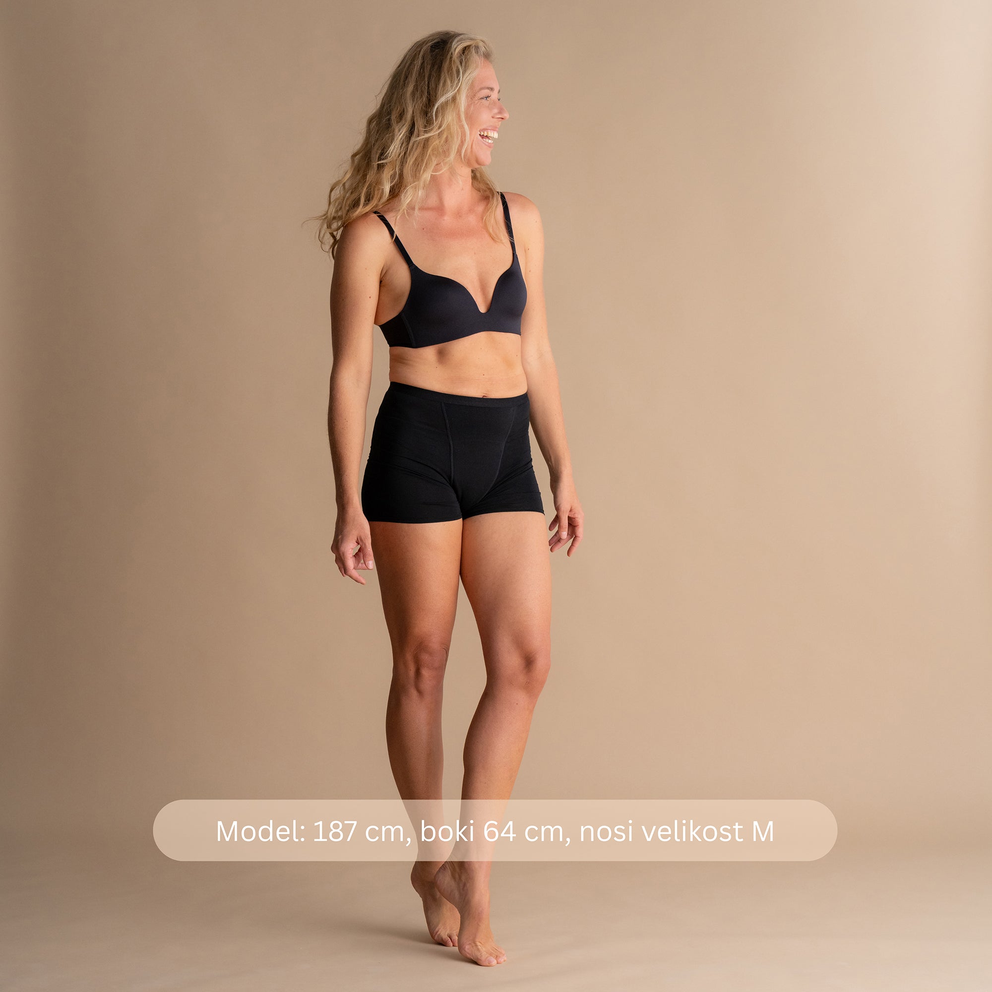 Model višine 187 cm z boki 64 cm nosi velikost M črnih Floena Leakproof Bamboo Sleep Short menstrualnih hlačk za spanje, z navedbo mere