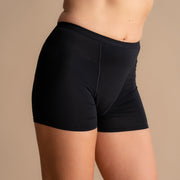 Sprednji pogled na črne Floena Leakproof Bamboo Sleep Short menstrualne hlačke za spanje na modelu pred bež ozadjem