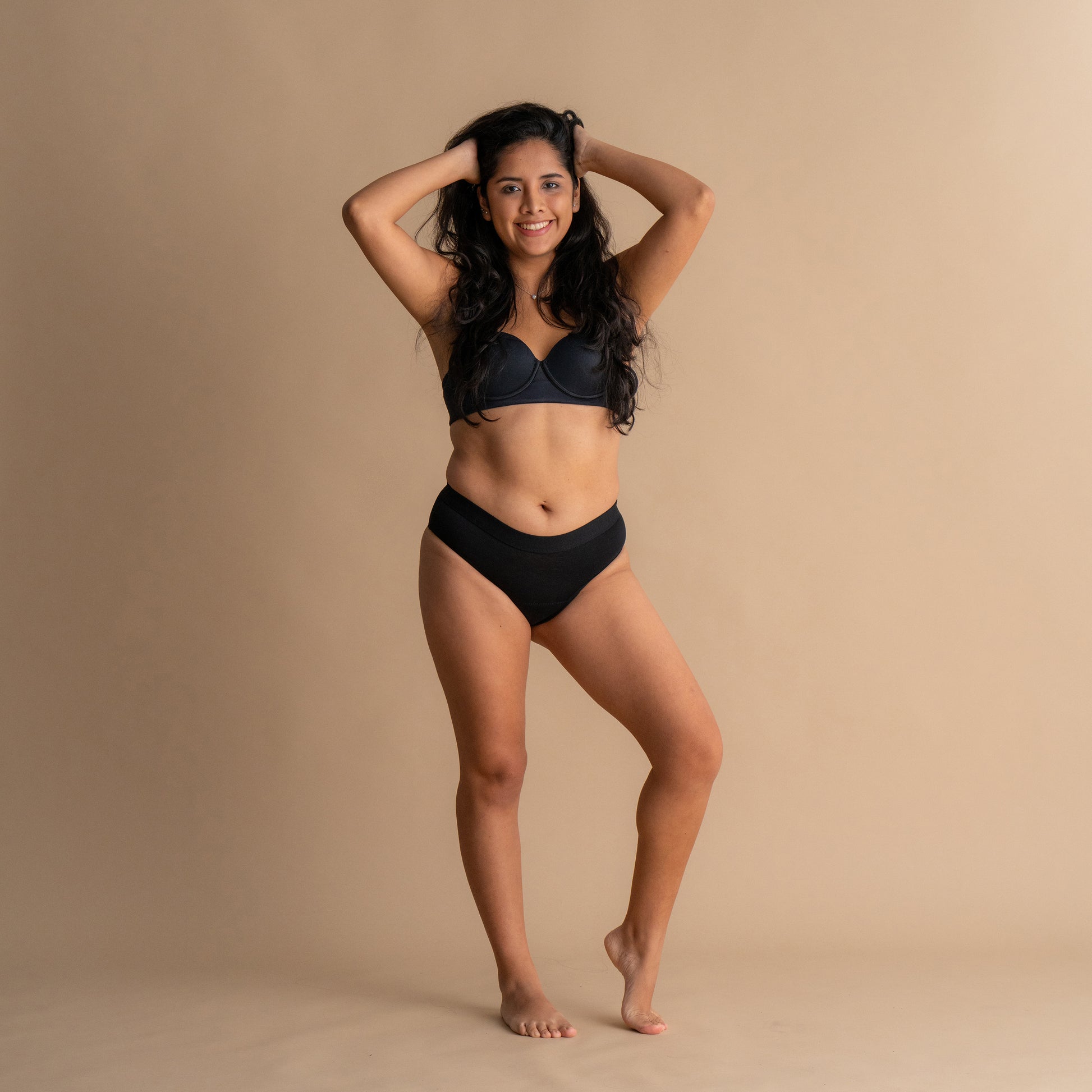 Celoten sprednji pogled na nasmejan model z rokami v laseh v črni Floena Leakproof Everyday Bamboo Bikini, bambusove menstrualne hlačke