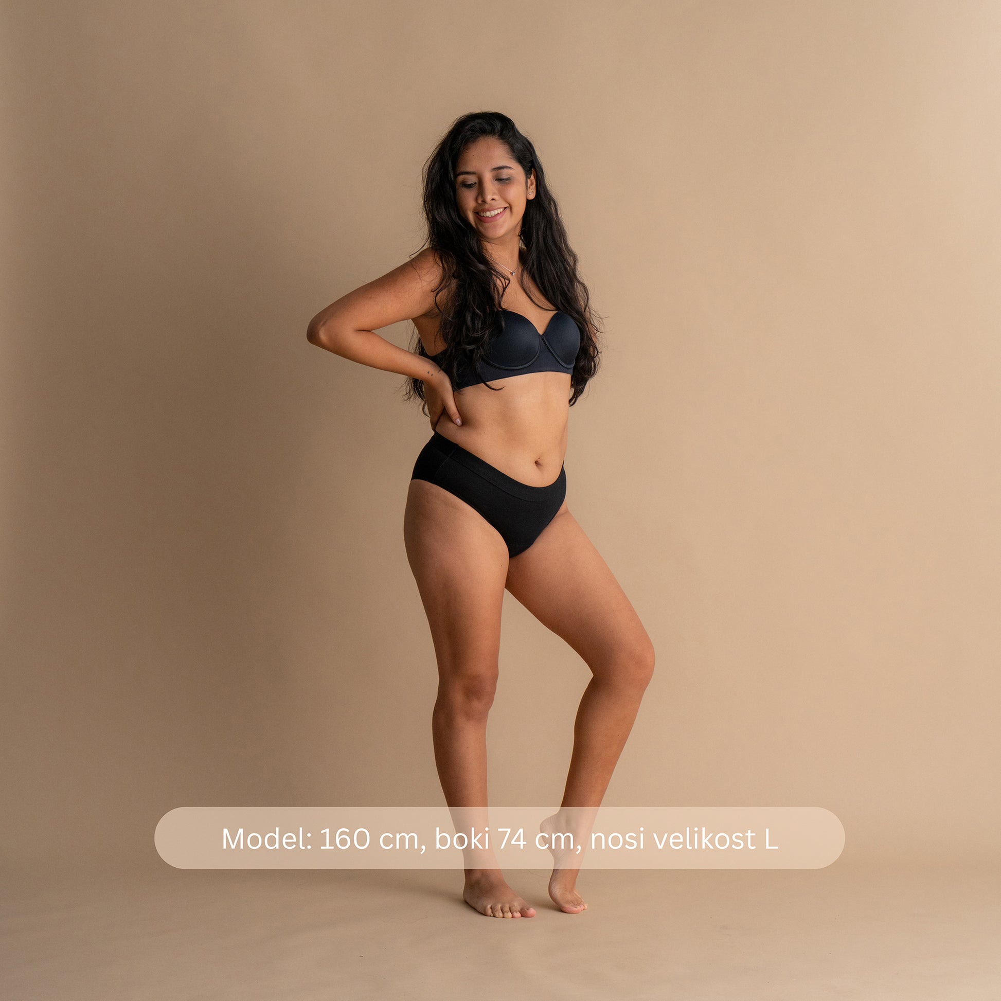 Model višine 160 cm z boki 74 cm nosi velikost L črne Floena Leakproof Everyday Bamboo Bikini, bambusove menstrualne hlačke, sprednji pogled z navedbo mere