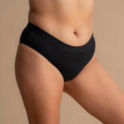 Celoten stranski pogled na model v črni Floena Leakproof Everyday Bamboo Bikini, bambusove menstrualne hlačke, z gladkim pasom