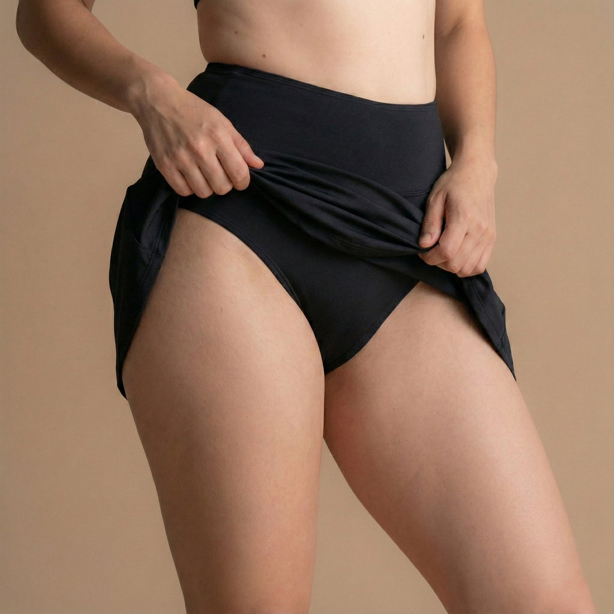 Sprednji stranski pogled na model v črnem Floena Leakproof Period Swim Skirt, menstrualno kopalno krilo, z visokim pasom in vodoodbojno tkanino