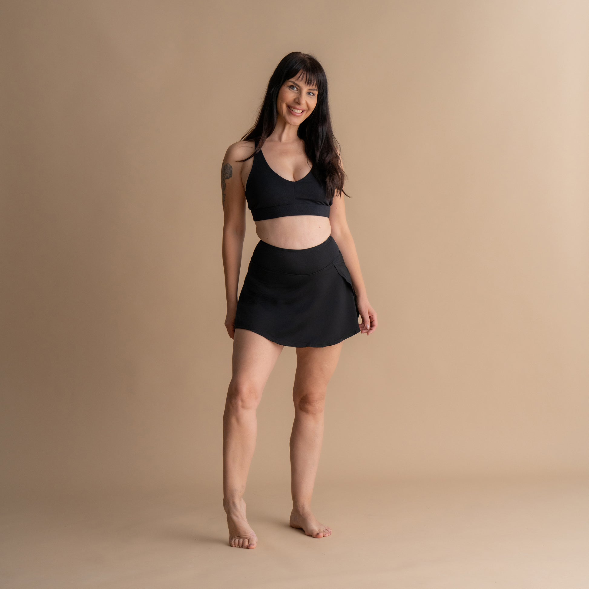 Celoten sprednji pogled na model v črnem Floena Leakproof Period Swim Skirt, menstrualno kopalno krilo, z ujemajočim bikini zgornjim delom
