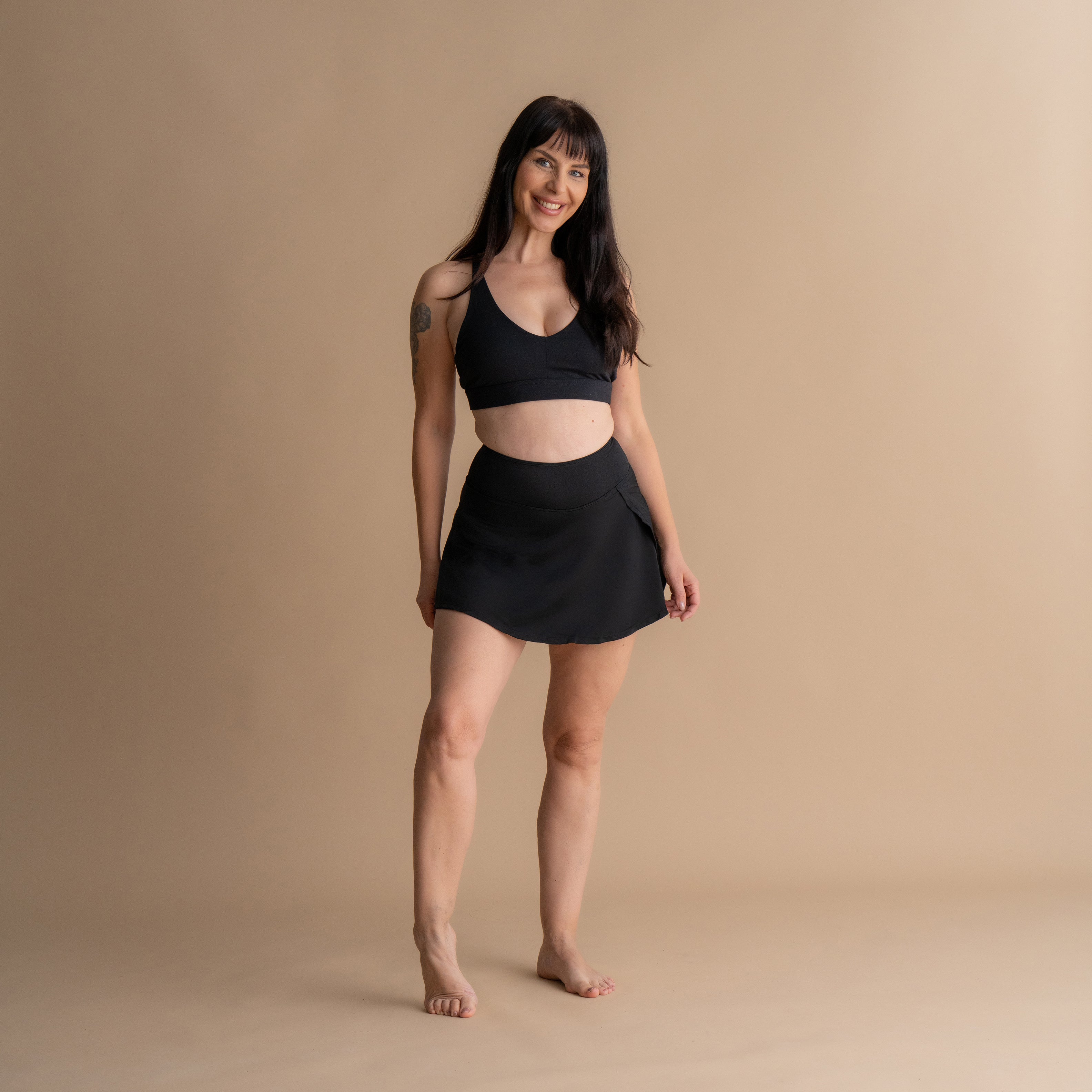 Celoten sprednji pogled na model v črnem Floena Leakproof Period Swim Skirt, menstrualno kopalno krilo, z ujemajočim bikini zgornjim delom