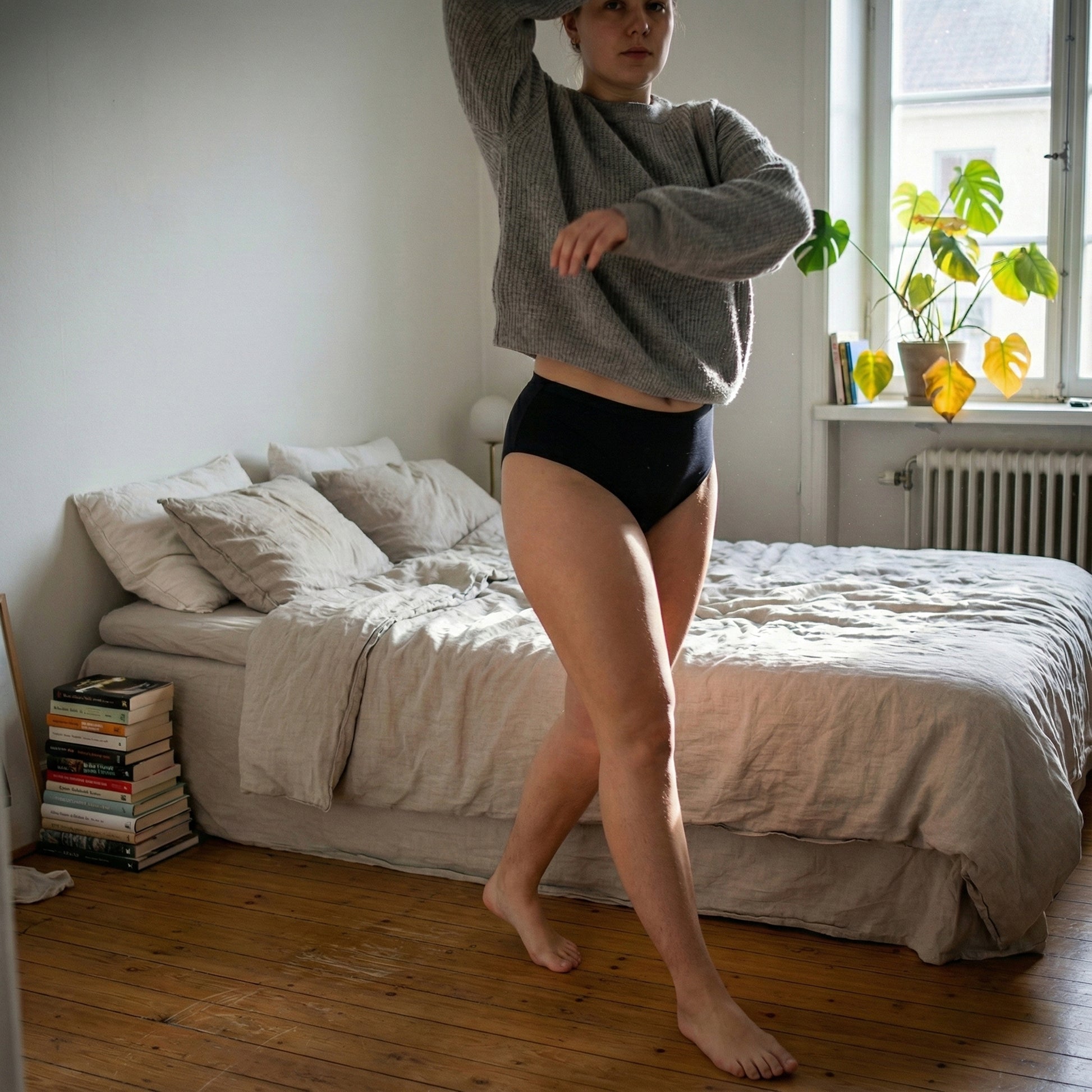 Model v sivem puloverju in črnih Floena Leakproof Seamless High Waist Brief, brezšivne visoko pasne menstrualne hlačke, hodi po sončni spalnici