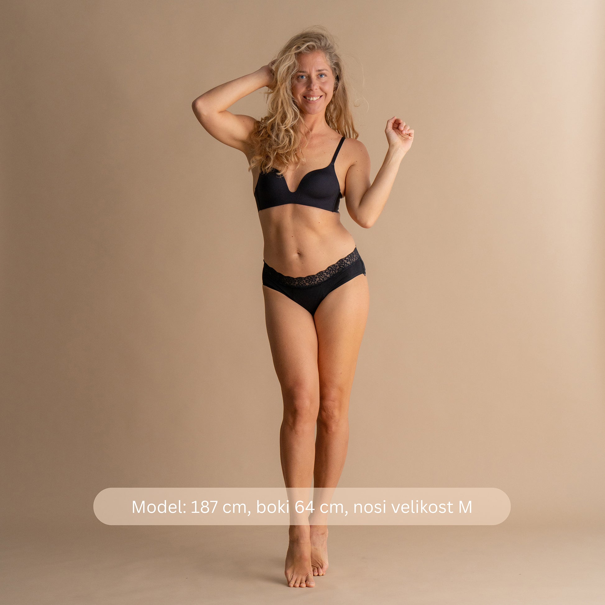 Model višine 187 cm z boki 64 cm nosi velikost M črnih Floena Leakproof Soft Cotton Brief, bombažne menstrualne hlačke, celoten sprednji pogled z navedbo mere