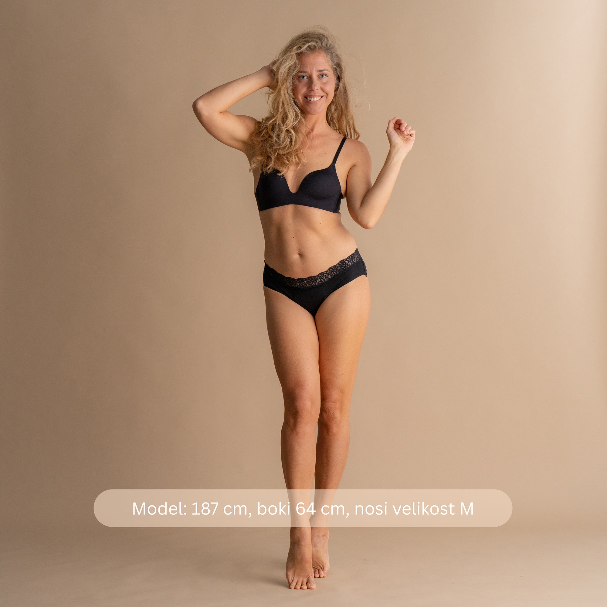 Model višine 187 cm z boki 64 cm nosi velikost M črnih Floena Leakproof Soft Cotton Brief, bombažne menstrualne hlačke, celoten sprednji pogled z navedbo mere