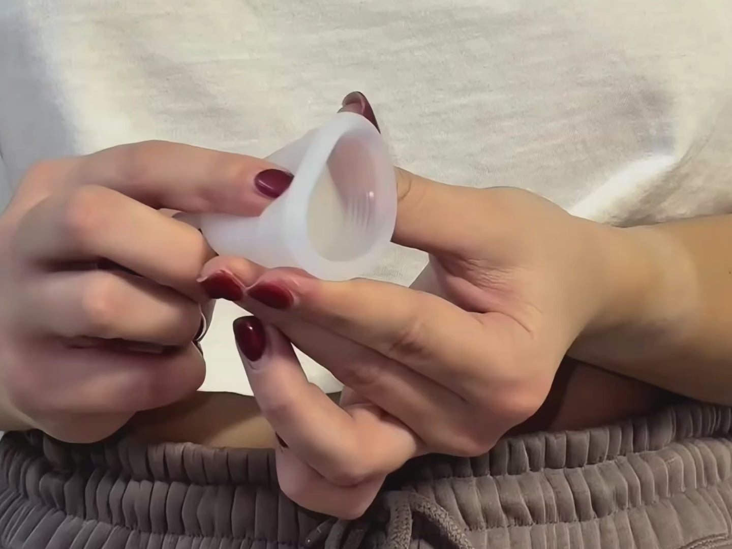 Naloži videoposnetek: Roke prikazujejo tehniko U-pregiba za vstavljanje menstrualne skodelice ali menstrualnega diska, s postopnim prikazom zlaganja.